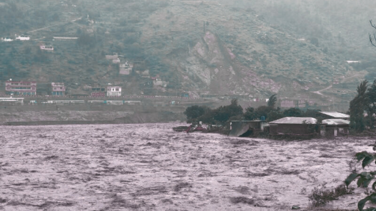 Local residents watch the Swat River overflow near Mingora after heavy pre‑monsoon rains on June 27 2025